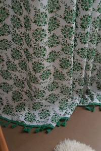Close-up of white fabric curtain with green floral print and matching fringe tassels