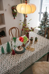 Detail of Christmas holly leaf print tablecloth with elegant green tassel edge decoration