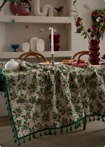 Detailed view of Christmas tablecloth with holly berry patterns and green fringe tassels