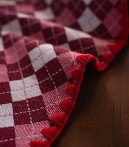 Close-up of red and white argyle tablecloth featuring exquisite scalloped crochet embroidery