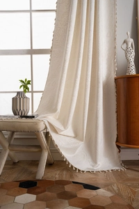 Detail of cream paisley jacquard curtain with elegant fringe trim and semi-shading fabric
