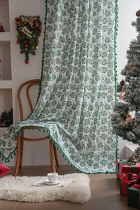 Detail of green Christmas curtain featuring holly leaf patterns and elegant tassel fringe
