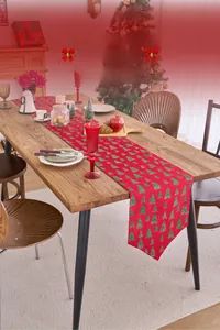 Close-up of red Christmas table runner with green tree patterns and golden details