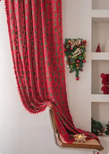 Detail of red Christmas curtain with green tree print and soft pom-pom trim texture