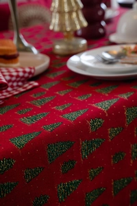 Detail der roten Weihnachts-Tischdecke mit grünen Bäumen und goldener Glitzertextur