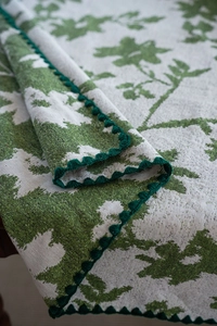 Detailaufnahme der Jacquard-Tischdecke mit grünem Blumenmuster und gehäkelter Spitzenkante