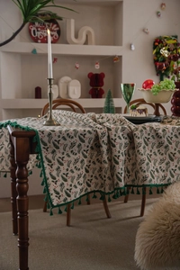 Close-up of Christmas holly leaf tablecloth with red berries and green tassel trim