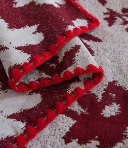 Dettaglio ravvicinato di tessuto jacquard rosso e bianco con bordo a frange pompon rossi