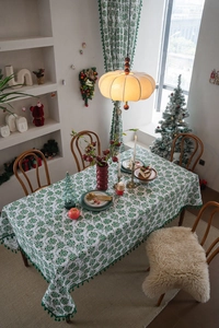 Detail of Christmas tablecloth with green floral prints and festive pom-pom fringe trim