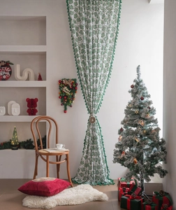 Detail of Christmas curtain with holly leaf print and green pom-pom fringe trim