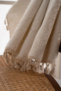 Macro shot of cream jacquard fabric with elegant floral patterns and fringe details