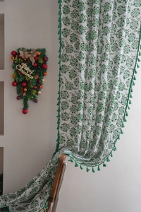 Detail of white semi-sheer curtain with green leaf pattern and decorative tassels