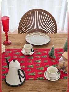 Close-up of red Christmas table runner featuring golden-edged green tree patterns