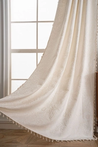 Detailed macro view of off-white jacquard curtains with paisley patterns and elegant tassel edges