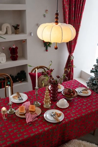 Detail der roten Weihnachtstischdecke mit grünen Baummotiven und eleganten Fransen
