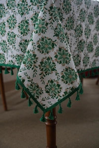 Detail of Christmas tablecloth with green poinsettia prints and elegant gold leaf accents