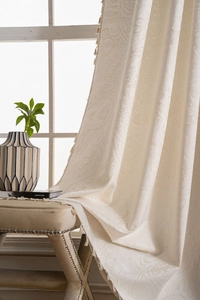 Detailed texture of cream paisley jacquard curtain with elegant handmade fringe tassels