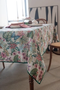 Detail of bohemian jacquard tablecloth featuring floral patterns and green pom-pom edges