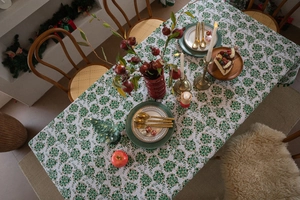 Detail of Christmas tablecloth with green and gold floral prints on white fabric