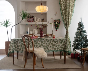 Close-up of holly berry print tablecloth with festive green pom-pom tassel fringe edges