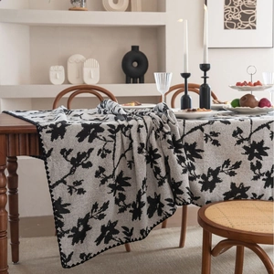 Tovaglia jacquard italiana con motivi floreali neri e bordi ondulati per sala pranzo