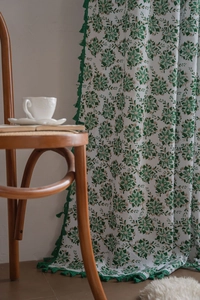 Detail of green floral curtain with elegant tassels and natural linen fabric texture