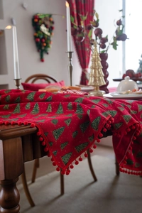 Detail eines roten Weihnachts-Tischläufers mit Tannenbäumen und roten Bommeln