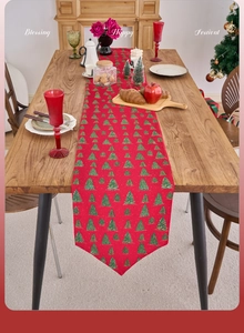Detail of red Christmas table runner featuring gold foil trees and festive dining decor