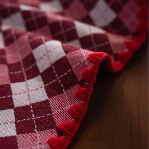Red and white checkered tablecloth with festive scalloped embroidery on a wooden table