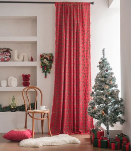 Detail view of red Christmas curtain featuring green tree patterns and hanging pom-pom trim