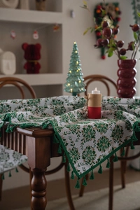 Close-up of festive Christmas tablecloth with green snowflake prints and tassels