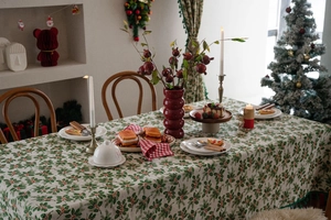 Close-up of Christmas holly leaf and red berry patterns on a cream table runner