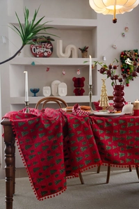 Detail der roten Weihnachtstischdecke mit grünen Bäumen und roten Bommel-Borten