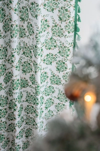 Detail of green holly leaf print on window curtain with decorative hanging tassels