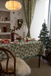 Macro detail of Christmas holly leaf print tablecloth with green tassel fringe edge
