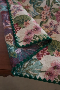 Detail of jacquard tablecloth with floral patterns and green lace crochet edges