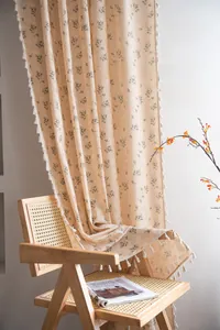 Detail of floral print linen curtain with white tassels on vintage wooden chair