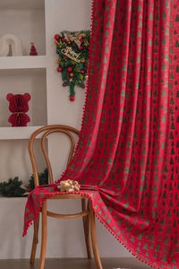 Detail of red Christmas curtain with green tree prints and plush ball pendant fringe