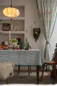 Detailed close-up of green Christmas tree patterns and elegant fringe on linen tablecloth