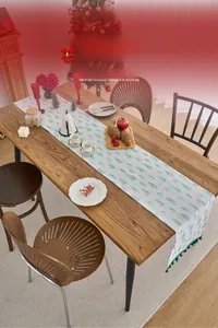 Detailed close-up of green Christmas tree patterns and tassels on a table runner