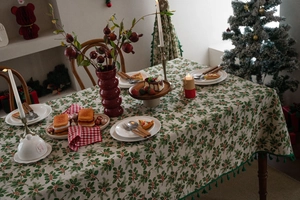 Close-up of Christmas holly leaf and red berry print tablecloth with elegant fringe trim