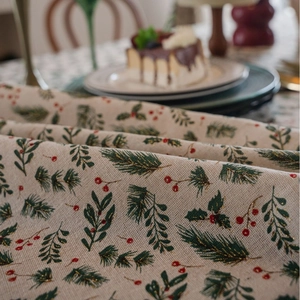 Christmas table runner with golden holly leaves and red berries on a linen texture