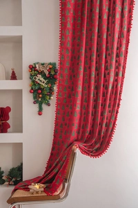 Detail of red Christmas curtain featuring green tree prints and plush pom-pom trim accents