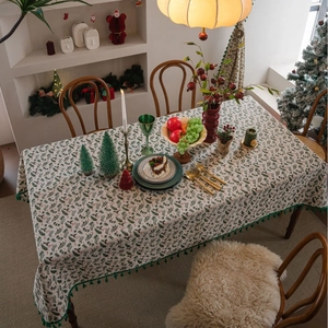 Christmas tablecloth with holly leaves, red berries, and green tassels on beige fabric