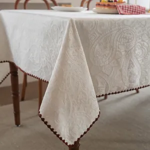 Beige jacquard tablecloth with vintage floral pattern and brown pom-pom fringe trim