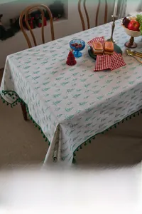 Detail of Christmas tablecloth featuring green pine tree patterns and dark green tassel fringe