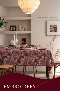 Close-up of floral and bird embroidery with scalloped red edges on festive tablecloth