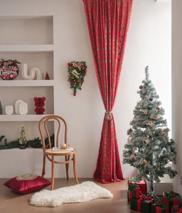 Detail of red Christmas curtain with green tree prints and soft pompom trim decoration