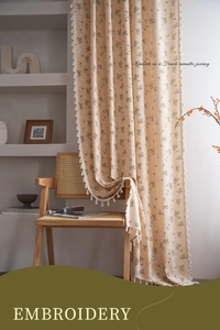 Close-up of floral embroidery and white tassel fringe on cream French style curtains