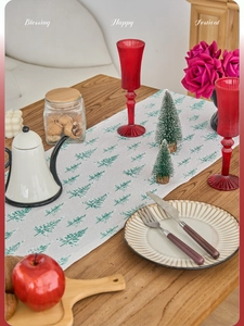 Detail of festive Christmas table runner with green pine trees on grey fabric background